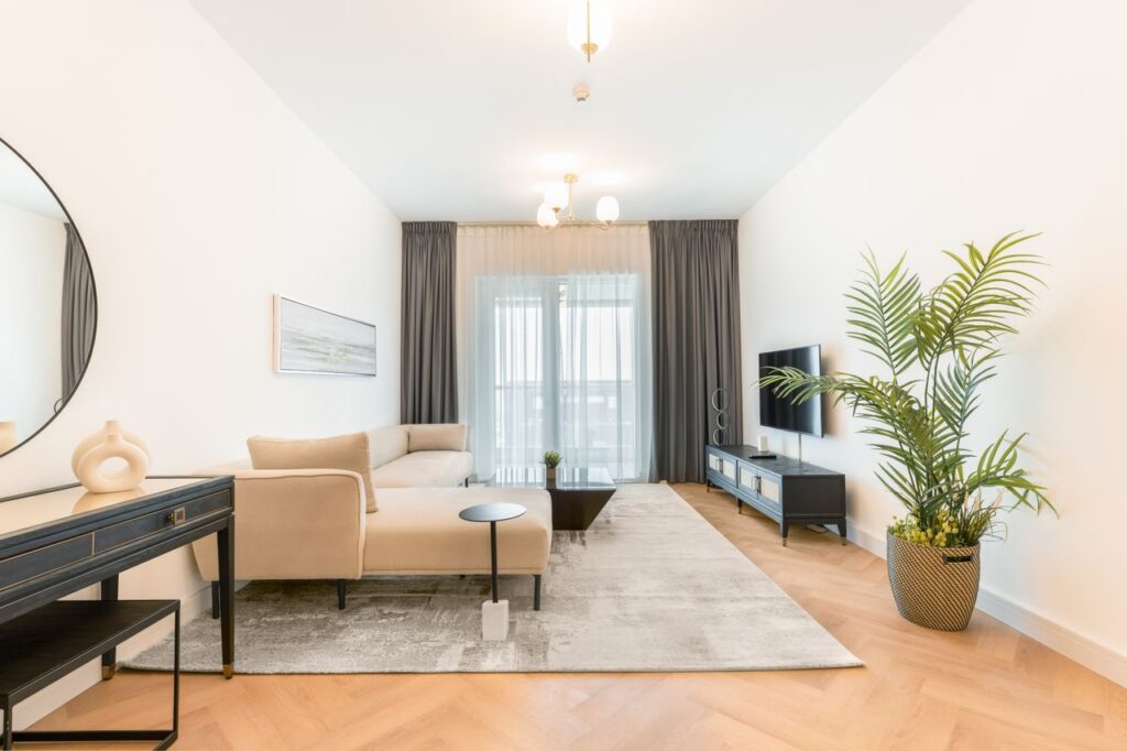 Bright and spacious modern living room with beige furniture and green plant decor.